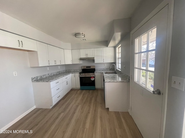 kitchen with white cabinets, light stone counters, light hardwood / wood-style flooring, and stainless steel stove