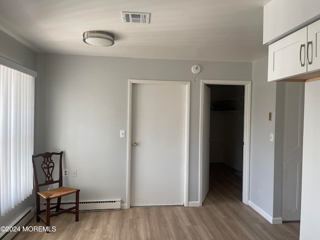 empty room with light hardwood / wood-style floors and a baseboard radiator