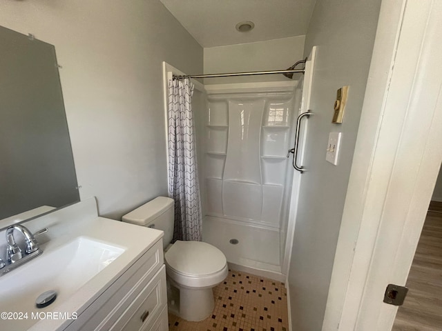 bathroom with hardwood / wood-style flooring, toilet, vanity, and walk in shower