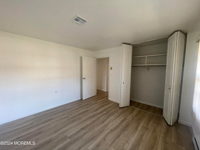 unfurnished bedroom featuring hardwood / wood-style floors and a closet