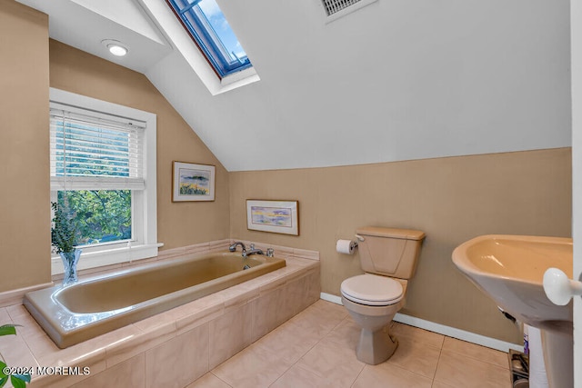 bathroom featuring toilet, vaulted ceiling with skylight, tile patterned floors, and tiled bath