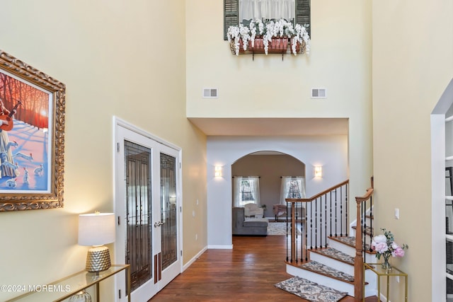 foyer with dark hardwood / wood-style floors, a high ceiling, and french doors