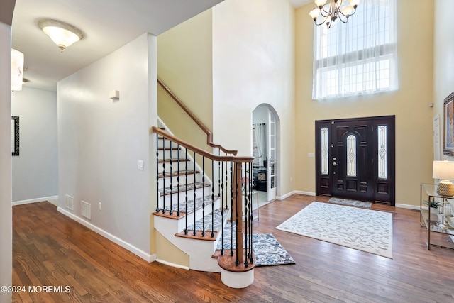 foyer featuring dark hardwood / wood-style flooring, a towering ceiling, and a notable chandelier