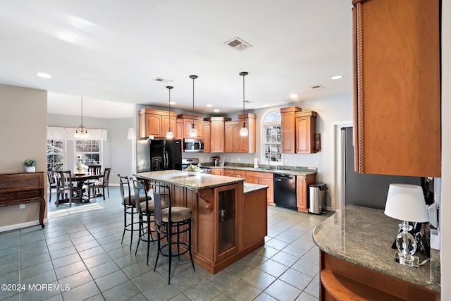 kitchen featuring a kitchen bar, sink, black appliances, light tile patterned floors, and a center island