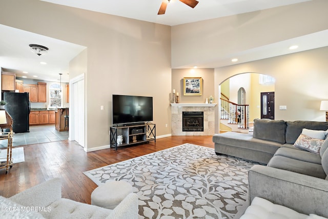 living room with ceiling fan, light hardwood / wood-style floors, and a tiled fireplace