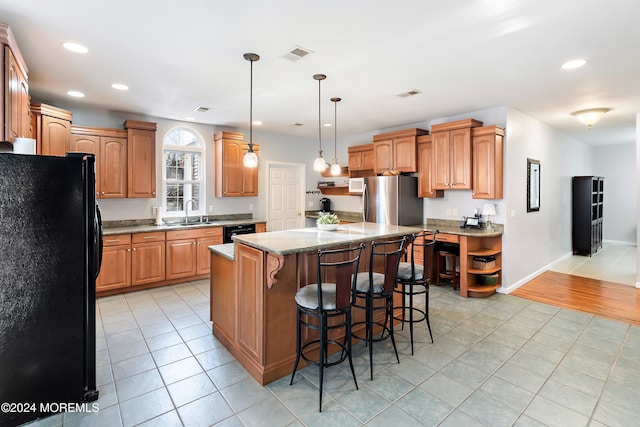 kitchen featuring sink, black appliances, light tile patterned floors, decorative light fixtures, and a center island