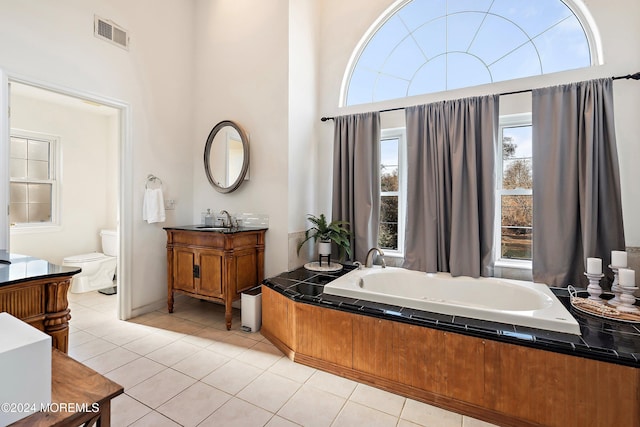 bathroom with a bathing tub, tile patterned flooring, a towering ceiling, toilet, and vanity