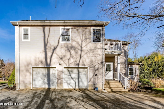 back of property with a balcony and a garage