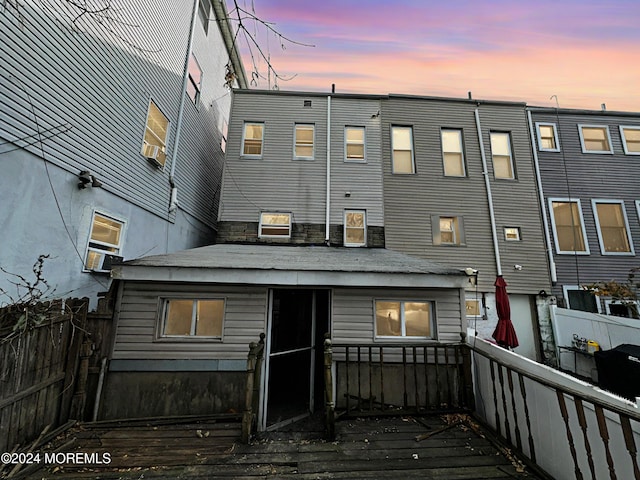 back house at dusk featuring a wooden deck