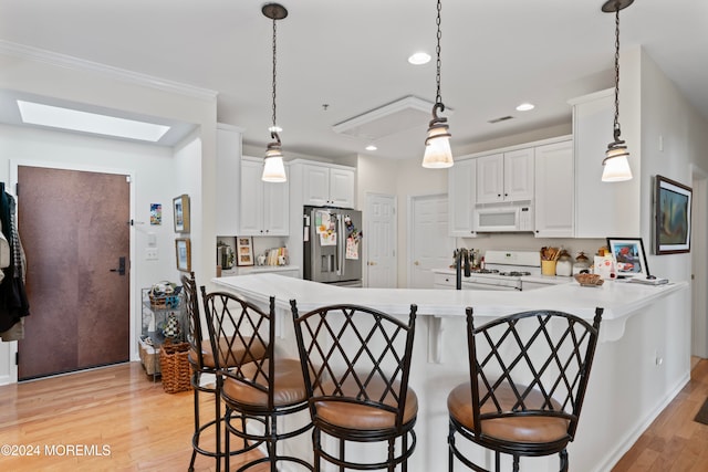 kitchen featuring white appliances, white cabinets, a skylight, light hardwood / wood-style flooring, and kitchen peninsula