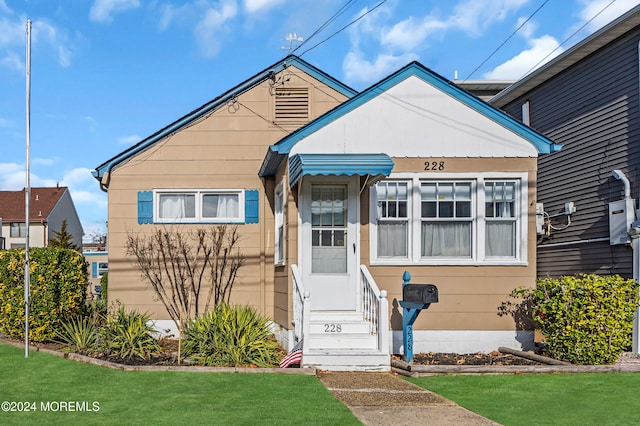 bungalow-style home with a front yard