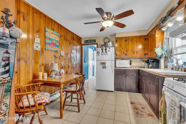 kitchen featuring wood walls, white appliances, sink, ceiling fan, and light tile patterned flooring