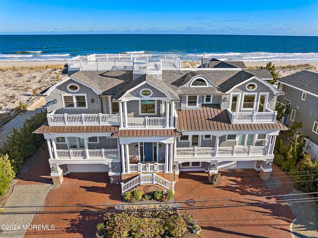 view of front of house featuring a water view, a balcony, and a beach view