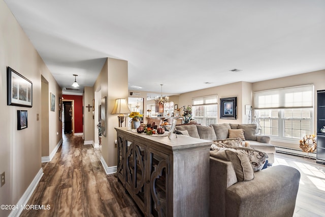 living room with a chandelier, wood-type flooring, and a baseboard heating unit