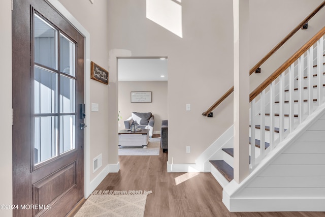 entryway with light wood-type flooring and a towering ceiling