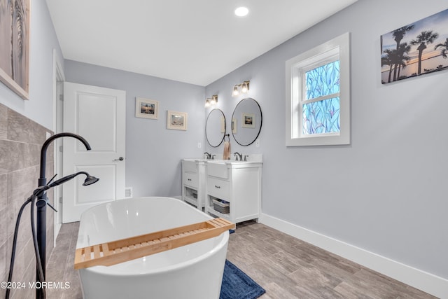 bathroom with a bath, vanity, and wood-type flooring