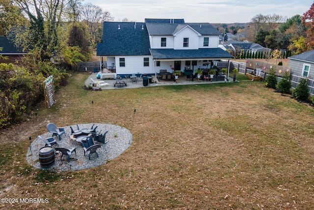 back of property with a lawn, a patio area, and an outdoor living space with a fire pit