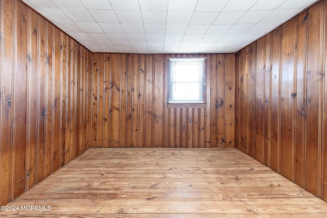 unfurnished room featuring light hardwood / wood-style floors and wooden walls