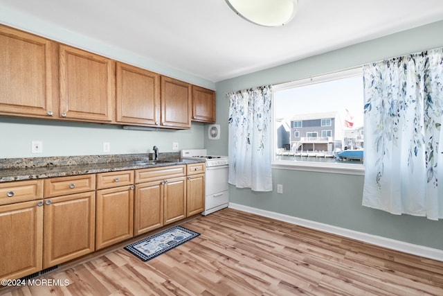 kitchen featuring light hardwood / wood-style floors, white gas range, sink, and dark stone counters