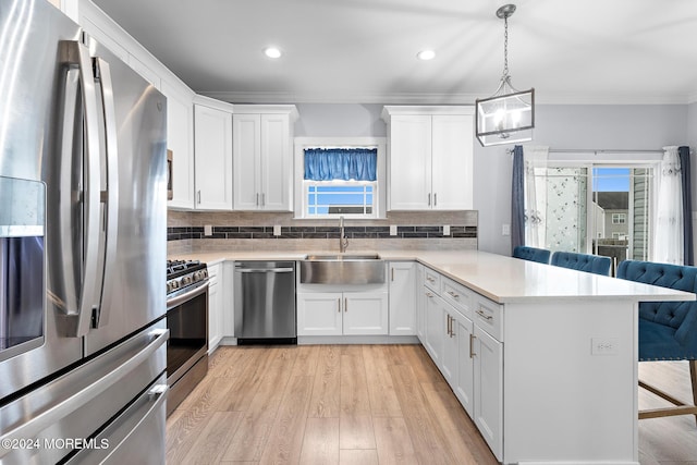 kitchen featuring a breakfast bar, appliances with stainless steel finishes, white cabinetry, and a wealth of natural light