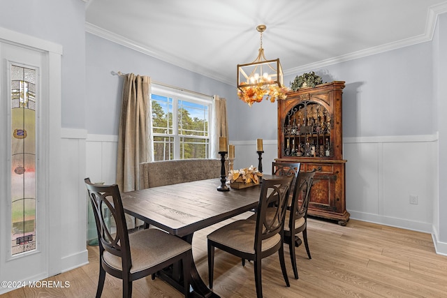 dining area featuring light wood-type flooring, crown molding, and an inviting chandelier