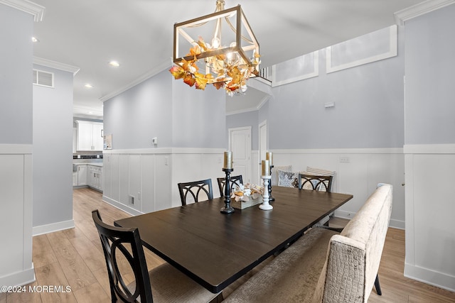 dining space featuring light wood-type flooring, crown molding, and a notable chandelier