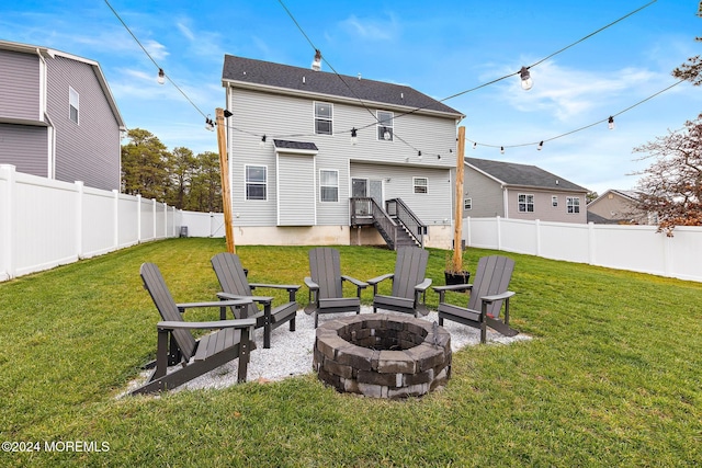 rear view of property with a yard and an outdoor fire pit