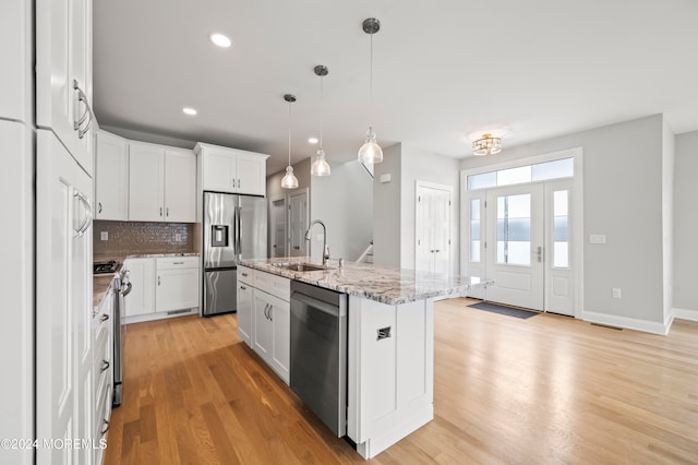 kitchen with a kitchen island with sink, white cabinets, stainless steel appliances, and light hardwood / wood-style floors