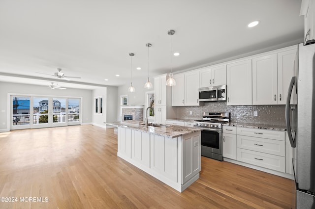 kitchen featuring stainless steel appliances, ceiling fan, sink, white cabinets, and hanging light fixtures