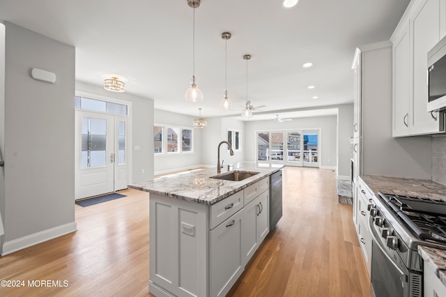 kitchen featuring stainless steel appliances, sink, pendant lighting, a center island with sink, and white cabinets