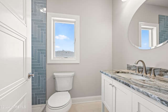 bathroom with tile patterned floors, a wealth of natural light, vanity, and toilet