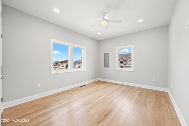 empty room with ceiling fan, electric panel, and light hardwood / wood-style flooring