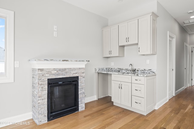 kitchen featuring white cabinetry, light hardwood / wood-style flooring, and light stone countertops