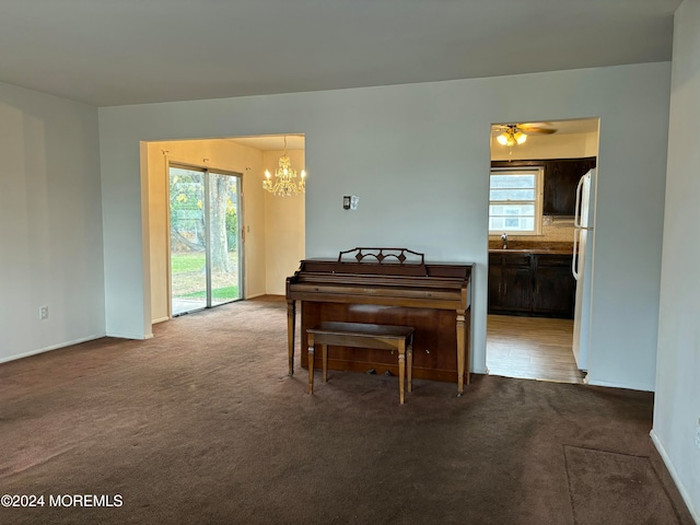 carpeted dining room with ceiling fan with notable chandelier and sink