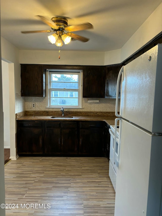 kitchen featuring white appliances, sink, ceiling fan, light wood-type flooring, and dark brown cabinets