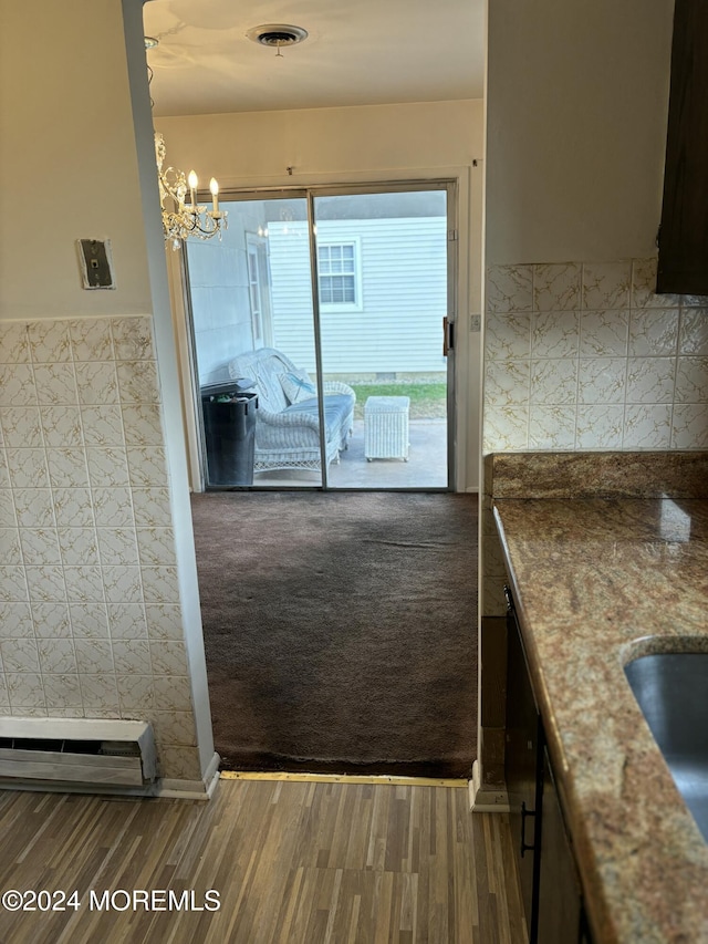 doorway with carpet flooring, sink, a baseboard heating unit, and a notable chandelier