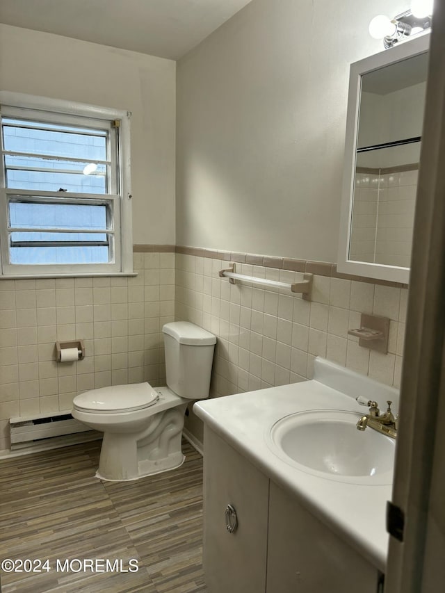 bathroom with toilet, wood-type flooring, tile walls, and a baseboard radiator