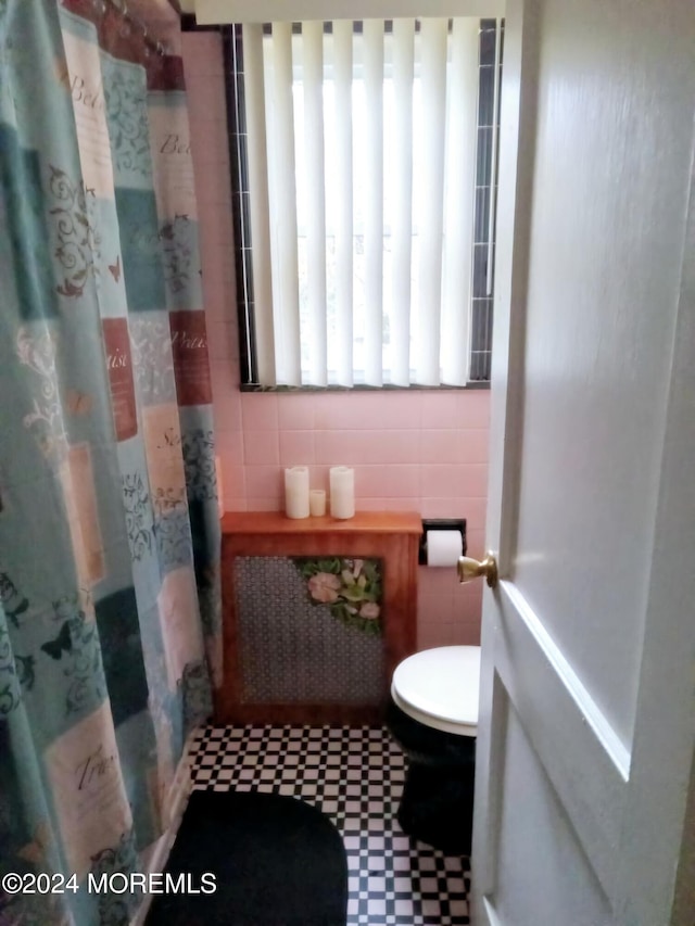 bathroom featuring a shower with curtain, toilet, and tile walls