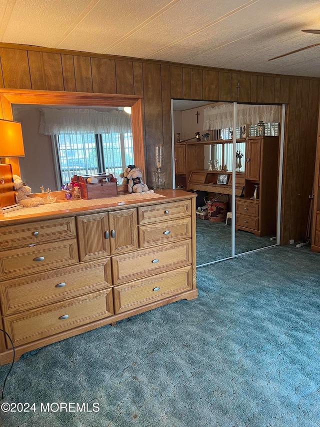 kitchen with wood walls, ceiling fan, a textured ceiling, and dark colored carpet