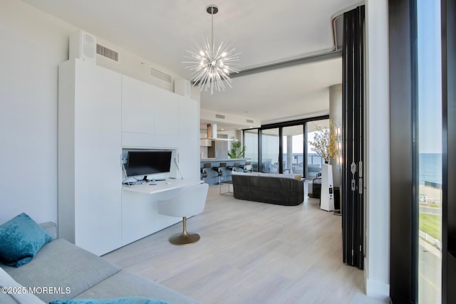 living room featuring a notable chandelier, a wall of windows, and light wood-type flooring