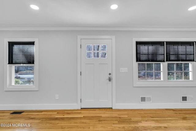 entryway with a wealth of natural light, crown molding, and light hardwood / wood-style floors