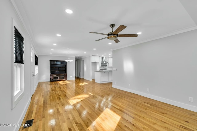 unfurnished living room featuring ceiling fan with notable chandelier, ornamental molding, and light hardwood / wood-style flooring