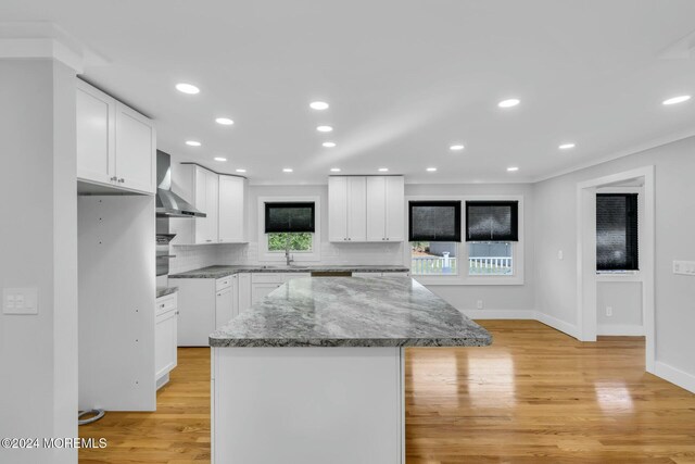 kitchen featuring a wealth of natural light, a center island, white cabinets, and dark stone counters