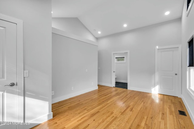 spare room with high vaulted ceiling and light hardwood / wood-style floors