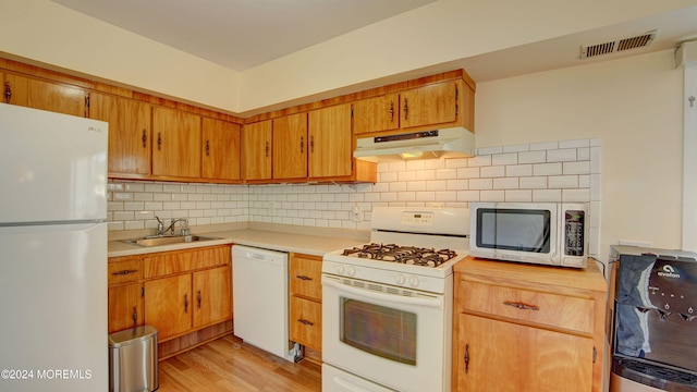 kitchen featuring white appliances, light hardwood / wood-style floors, backsplash, and sink