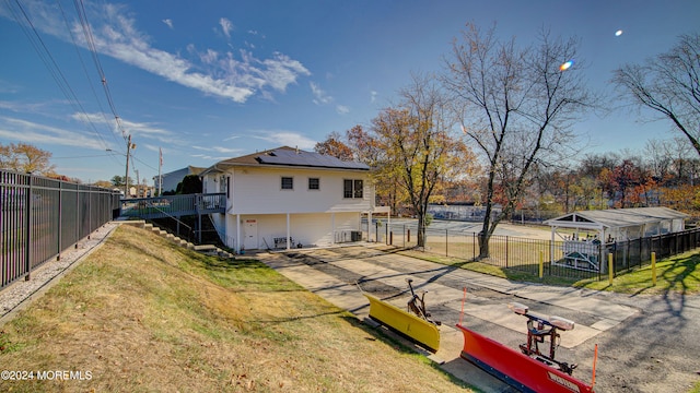 back of house with solar panels, central AC, and a lawn