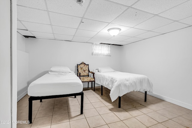 bedroom with a paneled ceiling and light tile patterned flooring