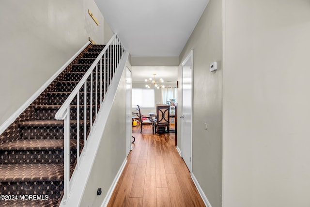 stairs with hardwood / wood-style floors and an inviting chandelier