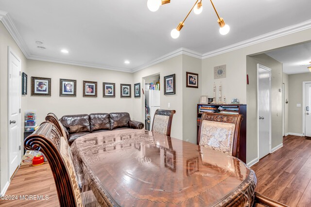 dining space featuring crown molding, wood-type flooring, and an inviting chandelier