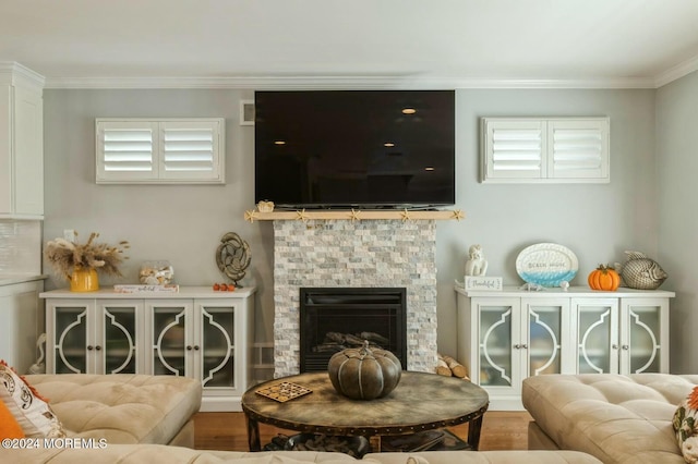 living room featuring hardwood / wood-style flooring, a stone fireplace, a wealth of natural light, and ornamental molding